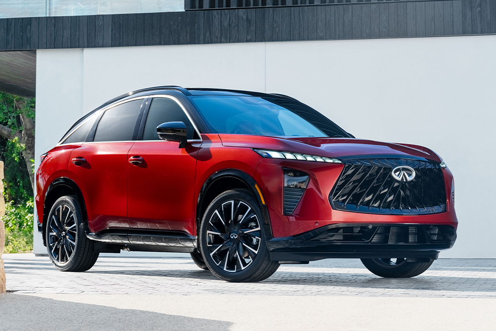 A sleek Infiniti QX65 red SUV with a bold front grille and shiny black wheels is parked on a modern driveway. The vehicle's design is sporty and luxurious.