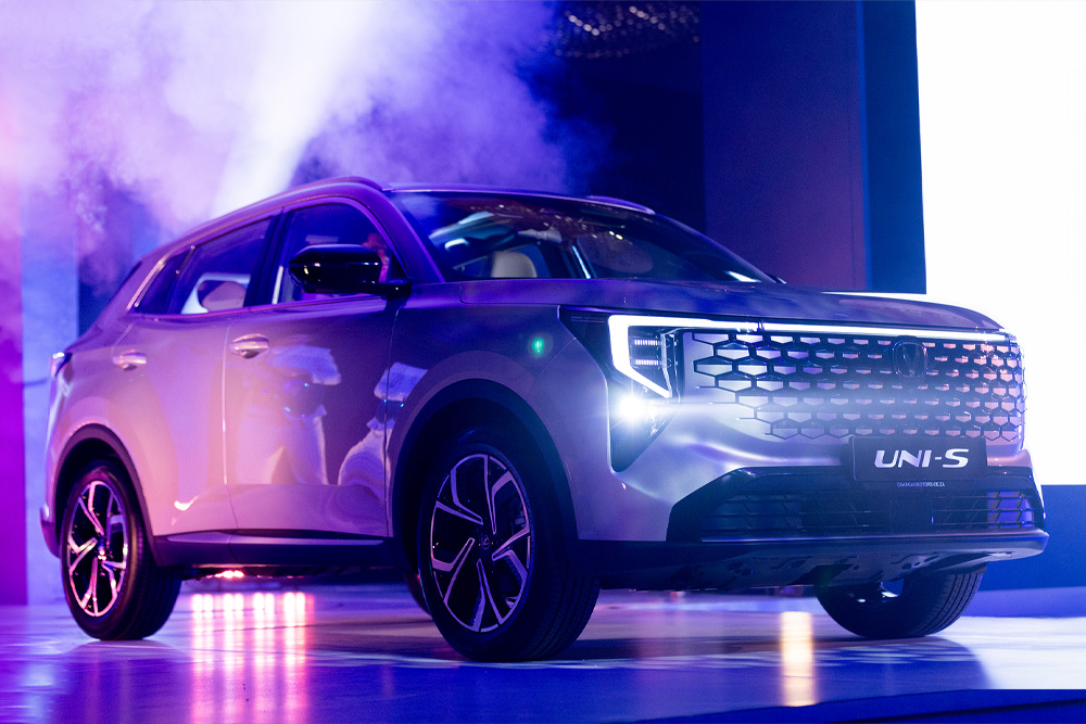 A sleek silver Changan UNI-S SUV is showcased under colorful blue and purple lighting, with smoke effects creating a dynamic, futuristic atmosphere at an auto event.