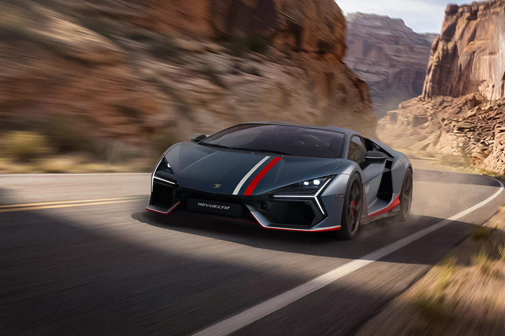 A sleek sports car Lamborghini Revuelto NA63 with red and white stripes speeds along a winding road in a rocky desert landscape, kicking up dust, conveying speed and excitement.