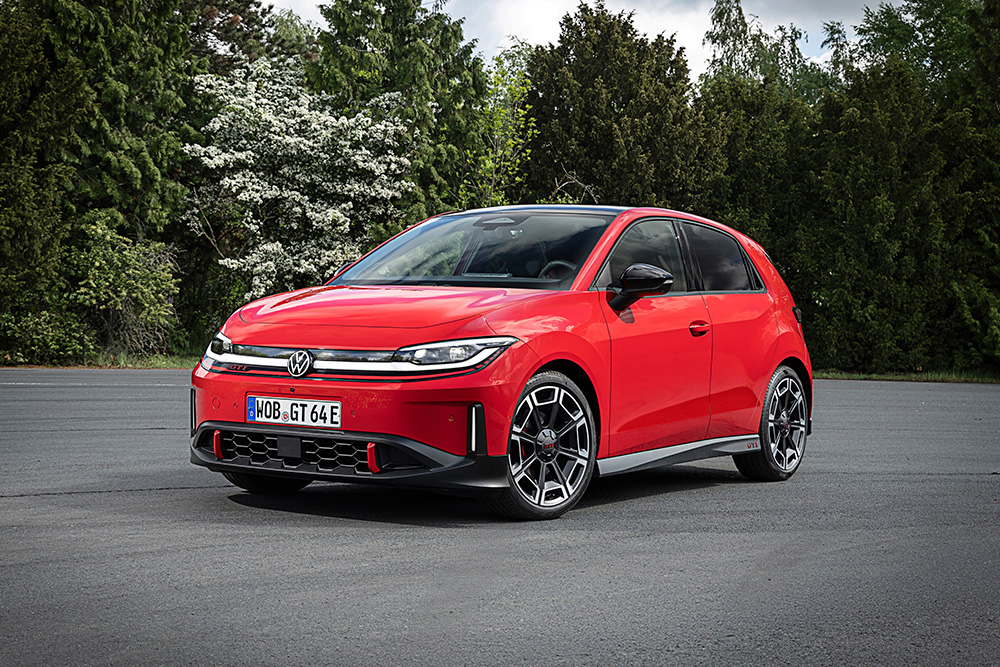 A vibrant red Volkswagen Polo GTI hatchback is parked on a paved surface, surrounded by lush greenery. The design is sleek and modern, conveying a sporty feel.