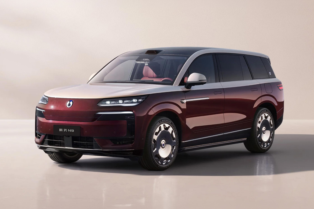 A sleek, modern BYD SUV with a burgundy and silver two-tone finish is parked indoors. The vehicle has tinted windows and a stylish, contemporary design.