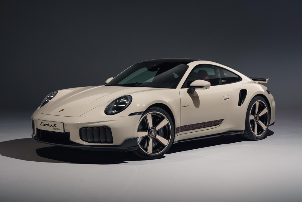 Sleek beige sports car Porsche 911 with dark rims parked in a dimly lit studio, showcasing aerodynamic curves and an upscale, modern design.