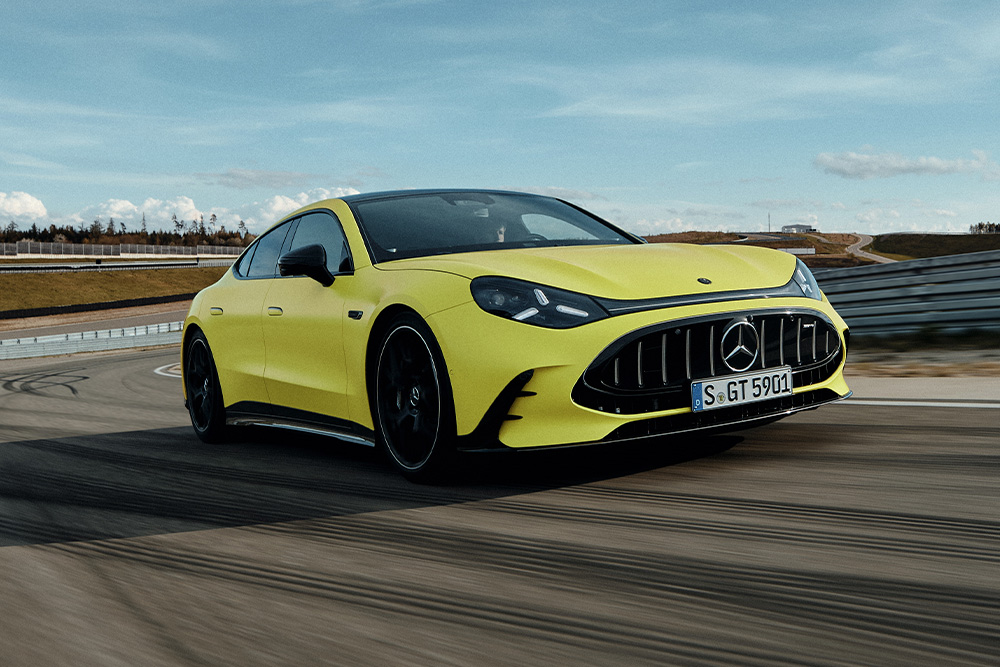 Vibrant yellow Mercedes-AMG GT 4-Door Coupe performance sedan driving fast along a professional racetrack.