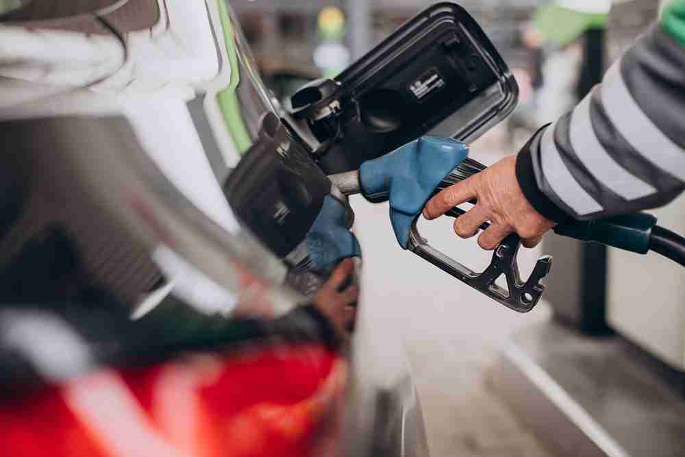 Close up of a person refueling a car with a blue petrol pump nozzle at a UAE fuel station for a regular refuel.