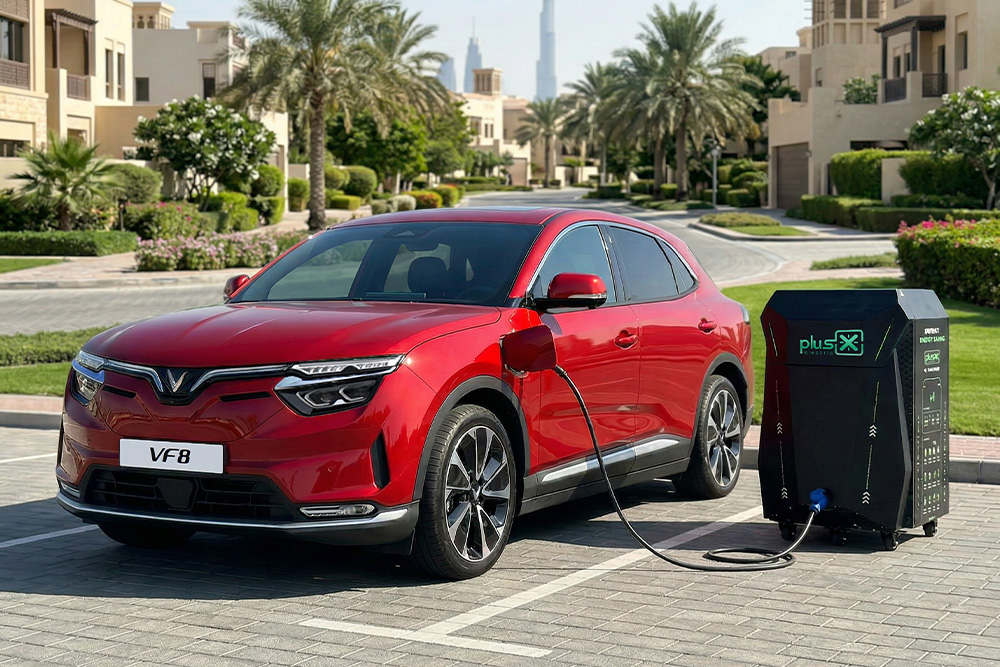 Red VinFast VF8 electric SUV vehicle plugged into a black portable charging station on a paved lot.