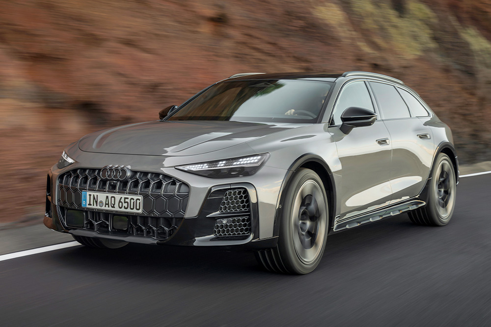 Sleek grey Audi luxury electric e-tron SUV cruising fast on an open asphalt highway road at daytime.